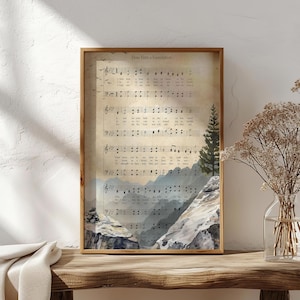 May include: Framed artwork featuring sheet music with the title "How Firm a Foundation." The artwork has a watercolor landscape of mountains and a pine tree. The frame is a warm brown color, and the overall aesthetic is vintage.