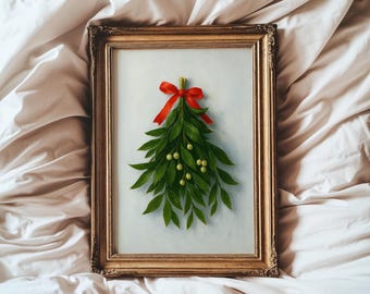 May include: A framed artwork featuring a green leaf arrangement with small yellow berries, tied with a red ribbon. The artwork is in a gold ornate frame, set against a white background.