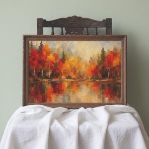 Peut inclure: Une peinture à l'huile dans un cadre en bois brun foncé représentant un paysage forestier automnal avec des arbres aux teintes vives rouges, orange et jaunes se reflétant dans une étendue d'eau calme, avec des coups de pinceau visibles.