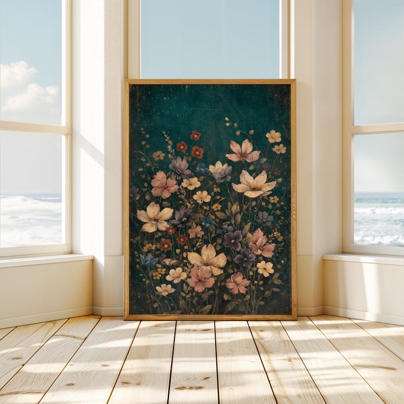 May include: A framed floral print featuring a dark teal background with a variety of flowers in shades of cream, pink, purple, and red. The artwork is displayed in a room with natural light and a view of the ocean.