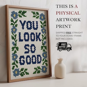 Puede incluir: Impresi&oacute;n art&iacute;stica enmarcada con el texto "YOU LOOK SO GOOD" en azul marino, rodeada por un borde floral. La impresi&oacute;n est&aacute; en un marco de madera clara. Un jarr&oacute;n blanco est&aacute; al lado de la obra de arte.