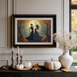 May include: A framed wall art print depicting two skeletons dancing in a forest filled with orange autumn leaves. The artwork is displayed in a black ornate frame above a table featuring three wooden candlesticks, small white pumpkins, and a vase.