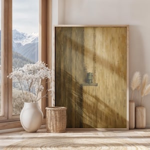 May include: A rectangular wall art piece in a light wood frame featuring an abstract painting with vertical brushstrokes in shades of ochre, mustard, and dark brown, with a small, centered, dark green rectangular element on a horizontal line.