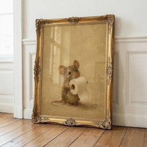 May include: A framed oil painting featuring a brown mouse holding a roll of white toilet paper. The artwork is encased in an ornate, antique-style gold frame with intricate carved details along the edges, set against a neutral beige background.