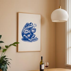 May include: A blue and white illustration of a frog sitting on a white background, holding a cup of coffee. The frog is wearing a blue shirt and has a blue hat. The frog is sitting on a white background.