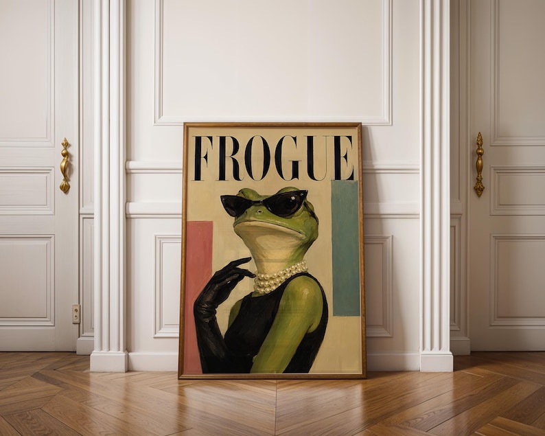 May include: A framed wall art print titled FROGUE featuring a green frog wearing black cat-eye sunglasses, a multi-strand pearl necklace, and a black sleeveless dress with a matching black glove. The background includes pink and teal rectangles.