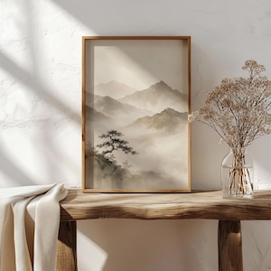 May include: A framed vertical wall art print featuring a monochromatic landscape of layered mountain ranges partially obscured by thick fog, with a single pine tree in the foreground. The artwork is displayed in a simple wooden frame.