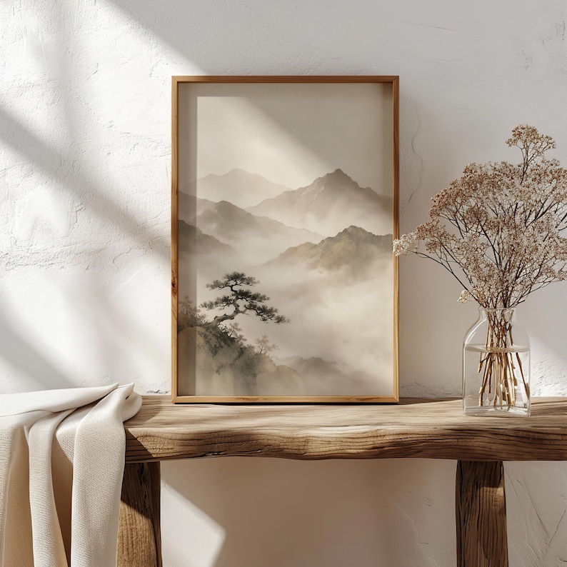 May include: A framed vertical wall art print featuring a monochromatic landscape of layered mountain ranges partially obscured by thick fog, with a single pine tree in the foreground. The artwork is displayed in a simple wooden frame.