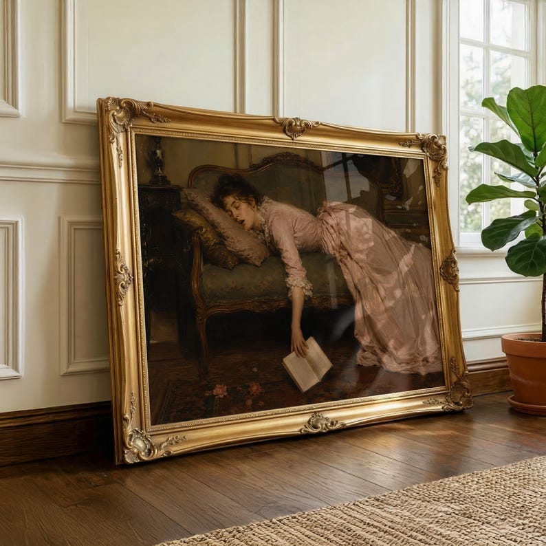 May include: A large rectangular painting in an ornate gold frame depicting a person in a long pink dress reclining on a dark green upholstered sofa. The person is resting their head on a pillow and holding an open book that hangs toward the floor.