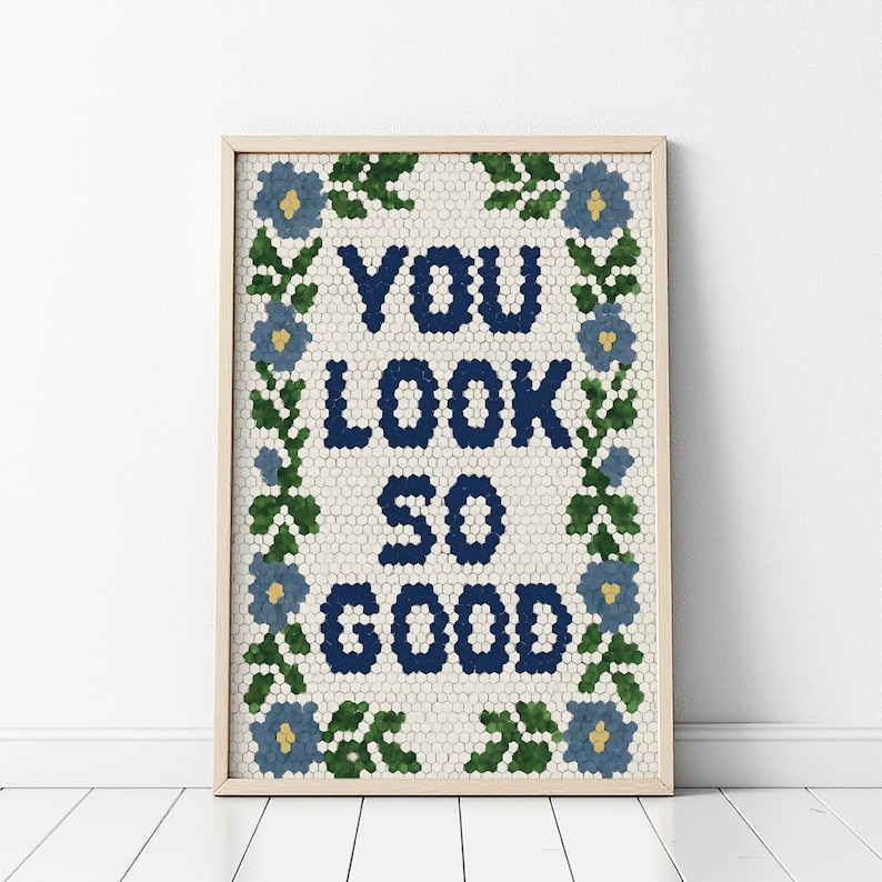 Puede incluir: Impresi&oacute;n art&iacute;stica enmarcada con las palabras "YOU LOOK SO GOOD" en azul marino, rodeada por un borde floral de flores azules y hojas verdes. El fondo es un patr&oacute;n de mosaico. El marco es de color madera clara.