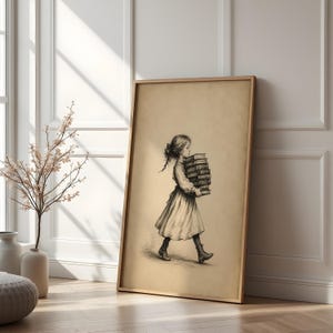 May include: A framed wall art print featuring a black and white pencil sketch of a young person with long hair tied back, wearing a dress and boots, walking while carrying a tall stack of thick books in their arms against a plain background.