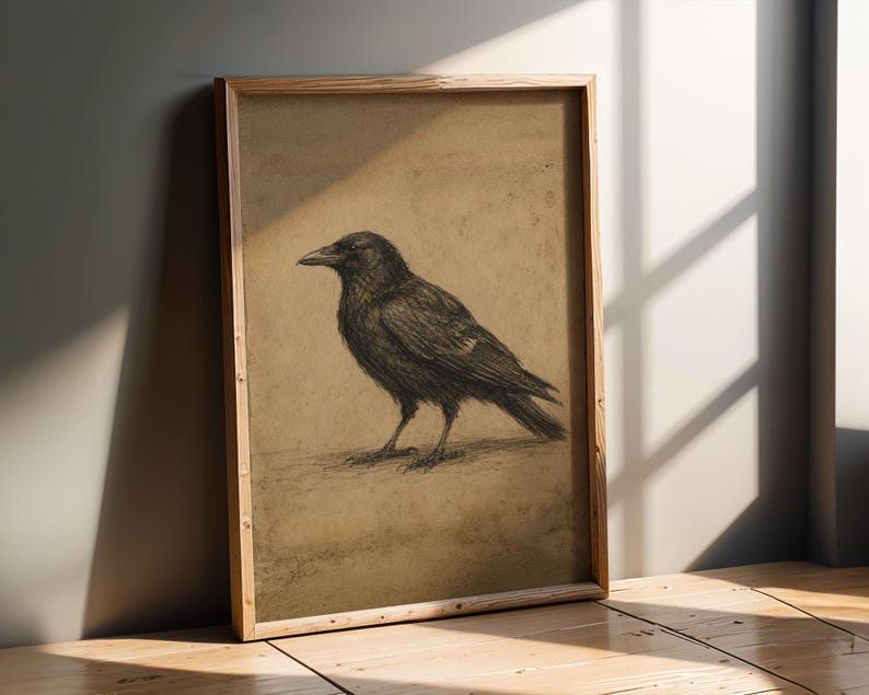 May include: A framed wall art print featuring a charcoal-style sketch of a black crow standing in profile. The bird is rendered with detailed dark strokes against a textured, muted tan background, enclosed in a simple light-toned wooden frame.