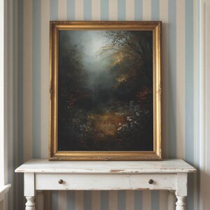 May include: A rectangular framed painting featuring a dark, moody forest scene with deep shadows, muted green foliage, and hints of golden light filtering through the trees. The artwork is encased in an ornate, metallic gold-toned frame.