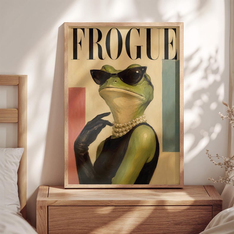 May include: A framed wall art print titled FROGUE featuring a green frog wearing black cat-eye sunglasses, a multi-strand pearl necklace, and a black sleeveless top with a matching black glove. The background includes vertical red and teal blocks.