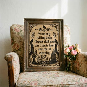 Puede incluir: Un bordado en punto de cruz enmarcado con hilo negro sobre tela beige. El texto dice, From my rotting body, flowers shall grow and I am in them and that is eternity. Incluye motivos de cuervos, l&aacute;pidas y una calavera decorativa.