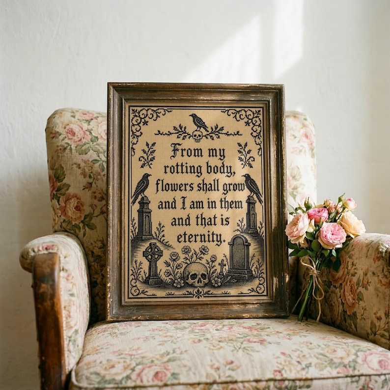 Puede incluir: Un bordado en punto de cruz enmarcado con hilo negro sobre tela beige. El texto dice, From my rotting body, flowers shall grow and I am in them and that is eternity. Incluye motivos de cuervos, l&aacute;pidas y una calavera decorativa.