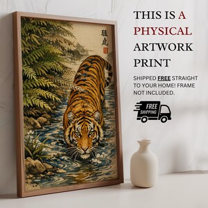 Puede incluir: Una impresi&oacute;n de arte f&iacute;sico enmarcada que representa un tigre en un arroyo, con texto japon&eacute;s. El tigre tiene rayas naranjas y negras, y la obra de arte est&aacute; ambientada en un entorno natural. La impresi&oacute;n incluye el texto "THIS IS A PHYSICAL ARTWORK PRINT".