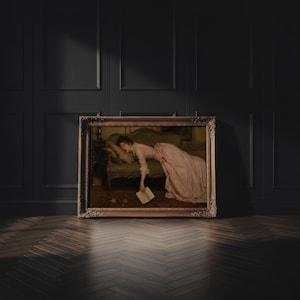 May include: A framed oil painting depicting a person in a long, pale pink dress reclining on a dark upholstered sofa. The person is asleep with one hand hanging down, holding an open book. The painting is enclosed in an ornate, dark gold frame.