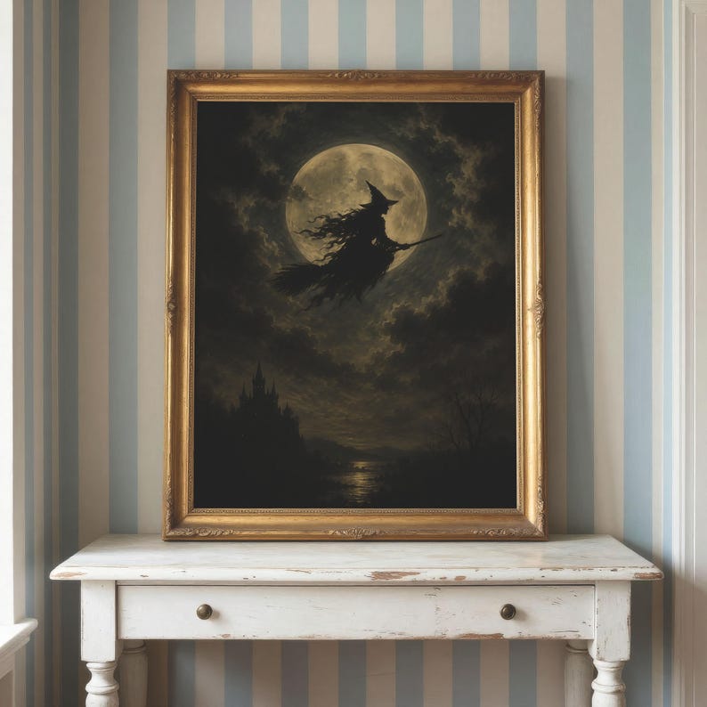 May include: A framed wall art print featuring a dark silhouette of a witch flying on a broomstick against a large, luminous full moon. The scene includes cloudy night skies and a distant castle silhouette, all encased in an ornate gold frame.
