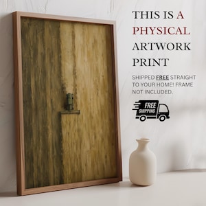 May include: A rectangular framed artwork print featuring a vertical abstract composition in shades of olive green and tan. The artwork displays a small, dark green tractor-like vehicle positioned centrally on a textured, brush-stroked background.