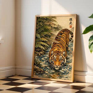 Puede incluir: Impresi&oacute;n art&iacute;stica enmarcada que representa un tigre en un arroyo, de inspiraci&oacute;n japonesa. El tigre tiene rayas naranjas y negras, con detalles de agua y follaje. El marco es de madera clara.