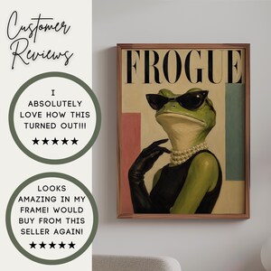 May include: A framed wall art print titled FROGUE featuring a green frog wearing black cat-eye sunglasses, a multi-strand pearl necklace, and black gloves against a cream background with pink and blue rectangular accents in a brown frame.