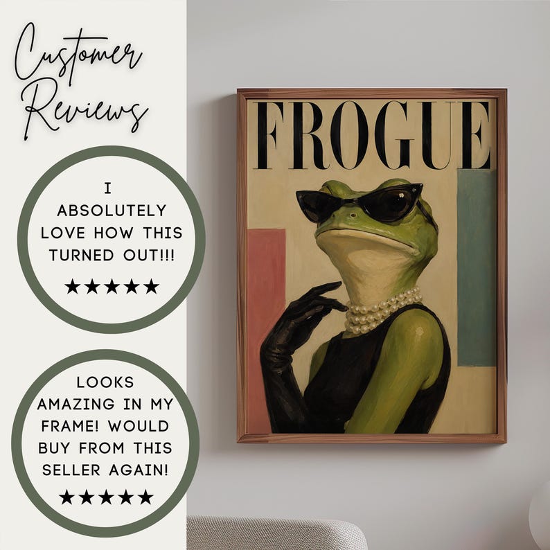 May include: A framed wall art print titled FROGUE featuring a green frog wearing black cat-eye sunglasses, a multi-strand pearl necklace, and black gloves against a cream background with pink and blue rectangular accents in a brown frame.