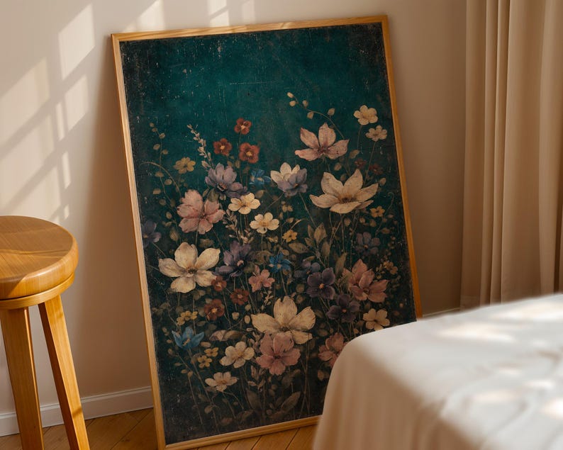 May include: A framed floral print featuring a dark teal background with a variety of flowers in shades of pink, purple, and white. The artwork is displayed in a room with a wooden stool and a bed.