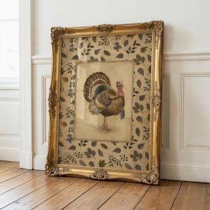 May include: A framed artwork featuring a central illustration of a turkey in profile, surrounded by a border of dark brown leaf patterns on a beige background. The piece is encased in an ornate, decorative gold-toned frame with intricate carvings.