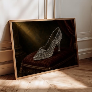 Pu&ograve; includere: Una stampa artistica incorniciata raffigurante una scarpa con tacco trasparente e testurizzata appoggiata su un cuscino di velluto rosso scuro. La scarpa presenta una punta affusolata e un tacco sottile su uno sfondo scuro e suggestivo.