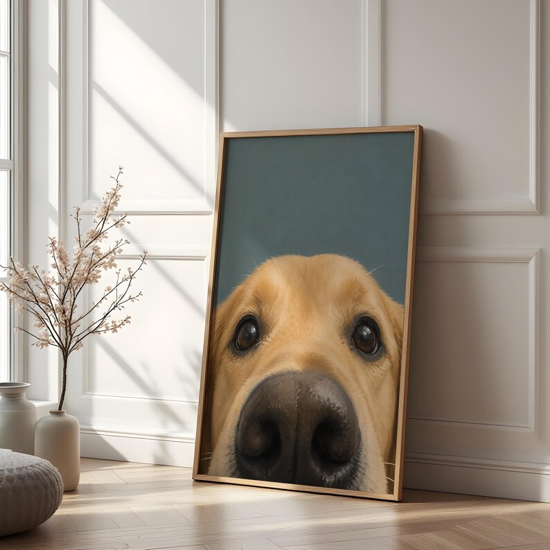 Puede incluir: Una impresi&oacute;n de arte mural vertical enmarcada que presenta un primer plano en gran angular del rostro de un perro de color dorado. El perro tiene ojos grandes de color marr&oacute;n oscuro y una nariz negra prominente y detallada centrada sobre un fondo verde azulado.