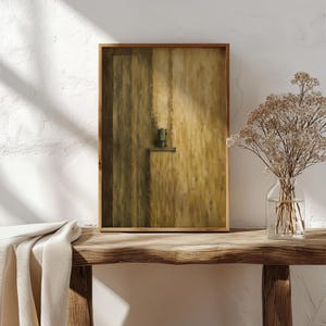 May include: A rectangular wall art print in a wooden frame featuring an abstract painting with vertical brushstrokes in shades of ochre, mustard yellow, and dark olive green, centered with a small, dark green geometric architectural element.