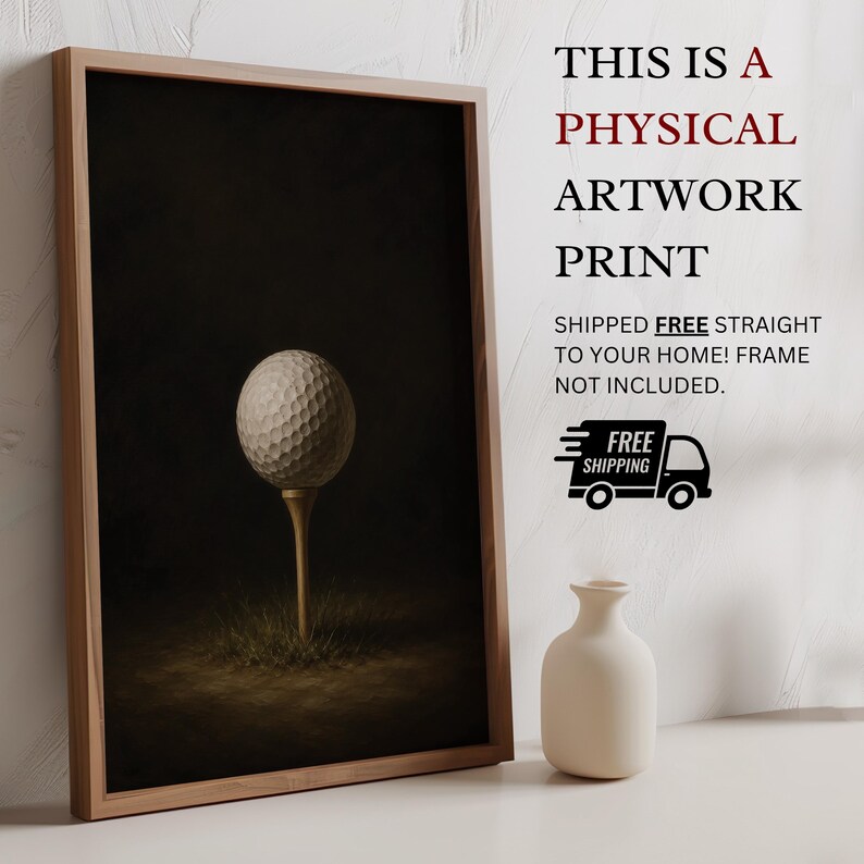 Op de afbeelding: Een ingelijste kunstdruk met een witte golfbal op een houten tee tegen een donkere achtergrond. De tekst luidt: THIS IS A PHYSICAL ARTWORK PRINT. SHIPPED FREE STRAIGHT TO YOUR HOME! FRAME NOT INCLUDED. Een kleine witte vaas staat ernaast.