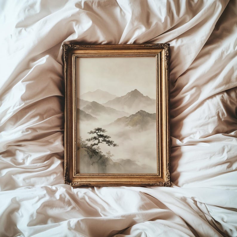 May include: A rectangular wall art piece in an ornate gold frame featuring a landscape painting of misty mountains and a single tree in the foreground. The artwork uses a muted color palette of soft grays, pale greens, and off-white tones.