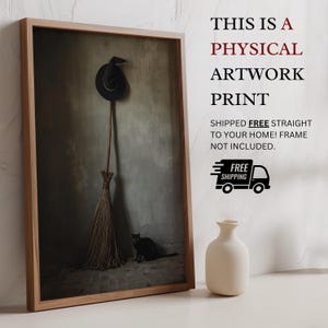 May include: A framed artwork print featuring a black witch hat hanging above a broomstick with a black cat sitting on the floor. The text reads: THIS IS A PHYSICAL ARTWORK PRINT SHIPPED FREE STRAIGHT TO YOUR HOME! FRAME NOT INCLUDED. FREE SHIPPING.