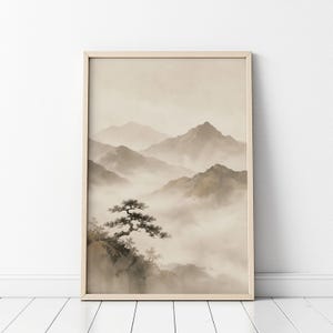 May include: A framed wall art print featuring a monochromatic landscape illustration of jagged mountain peaks partially obscured by thick, rolling fog. A single gnarled pine tree grows on a rocky cliff in the foreground, rendered in soft beige and brown tones.