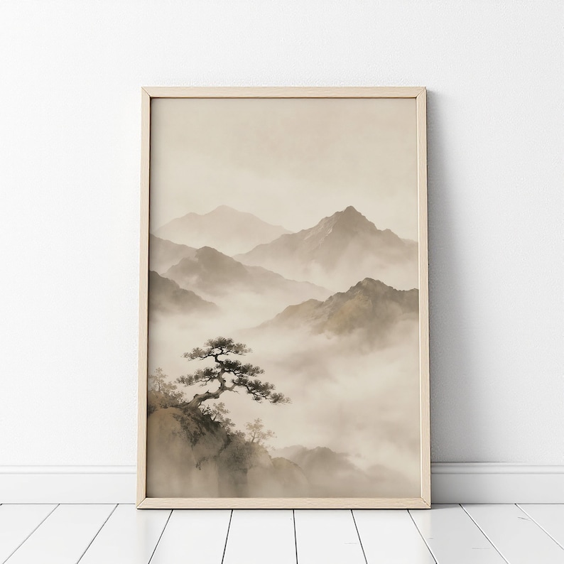 May include: A framed wall art print featuring a monochromatic landscape illustration of jagged mountain peaks partially obscured by thick, rolling fog. A single gnarled pine tree grows on a rocky cliff in the foreground, rendered in soft beige and brown tones.