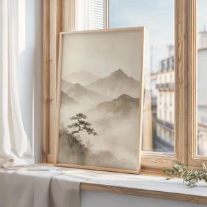May include: A vertical rectangular framed print featuring a monochromatic landscape illustration of layered mountain ranges partially obscured by thick fog, with a single gnarled tree perched on a rocky cliffside in the foreground.