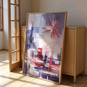 Könnte beinhalten: Abstrakter Kunstdruck mit einem farbenfrohen Design in Rot-, Weiß- und Blautönen. Der Druck ist in einem hellen Holzrahmen gerahmt und lehnt an einem Holzschrank.