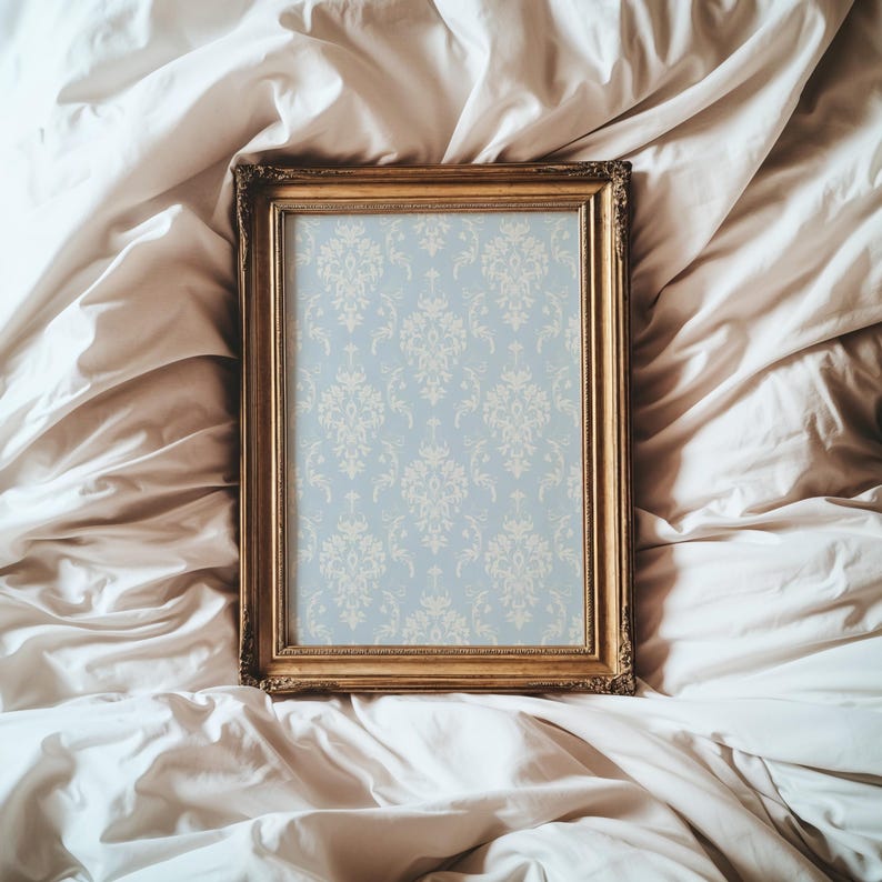 May include: A rectangular picture frame with an ornate gold finish containing a light blue insert featuring a repeating cream-coloured damask pattern. The frame has a detailed, textured border and is positioned vertically in the centre.