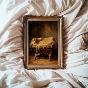May include: A framed painting depicting a manger scene. The artwork features a wooden manger filled with straw, set against a warm, golden background. The frame is ornate with a gold finish, adding to the traditional aesthetic.