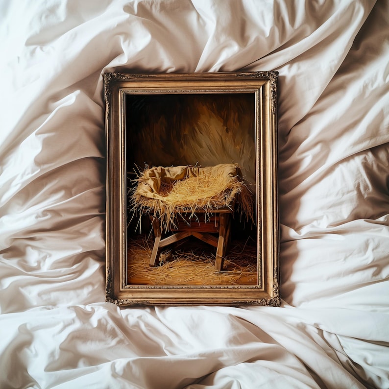May include: A framed painting depicting a manger scene. The artwork features a wooden manger filled with straw, set against a warm, golden background. The frame is ornate with a gold finish, adding to the traditional aesthetic.