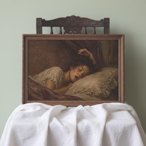 May include: A rectangular framed oil painting depicting a person sleeping in a bed with a ruffled pillow. The artwork features warm, muted tones, dark drapery, and a textured wall background, all encased in a dark brown wooden frame.
