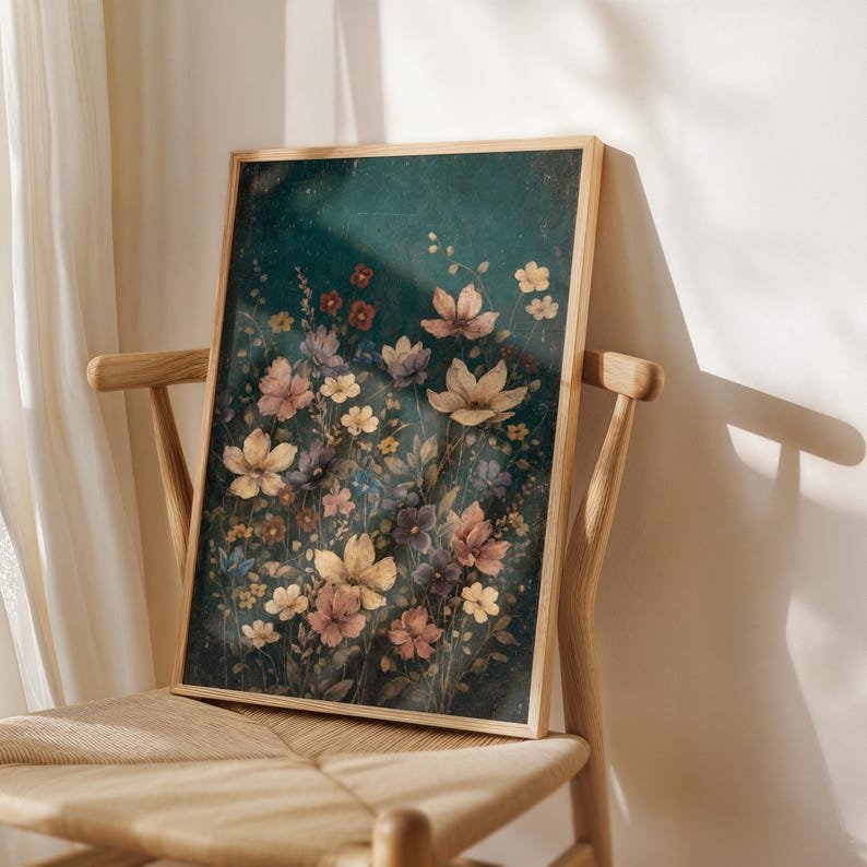 May include: A framed floral art print featuring a variety of flowers in shades of cream, pink, and purple against a dark teal background. The artwork is displayed on a wooden chair, showcasing the print's colors and details.