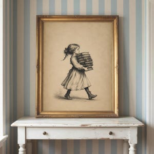 May include: A framed wall art print featuring a black and white sketch of a young person with hair tied back, wearing a dress and boots, walking while carrying a stack of five books. The artwork is enclosed in a rectangular gold-toned frame.