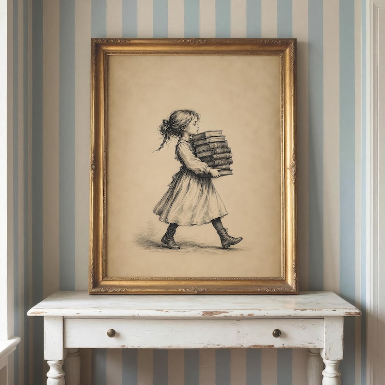 May include: A framed wall art print featuring a black and white sketch of a young person with hair tied back, wearing a dress and boots, walking while carrying a stack of five books. The artwork is enclosed in a rectangular gold-toned frame.