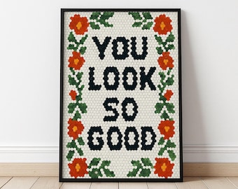 May include: Framed art print with the words "YOU LOOK SO GOOD" in black, surrounded by a floral border of orange flowers and green leaves. The background is a mosaic pattern. The frame is black.