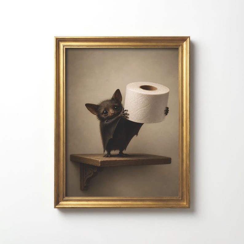 Puede incluir: Una l&aacute;mina de arte enmarcada que muestra un peque&ntilde;o murci&eacute;lago de pelaje oscuro de pie sobre un estante de madera. El murci&eacute;lago sostiene un rollo de papel higi&eacute;nico blanco con sus alas. La obra est&aacute; en un marco rectangular dorado.