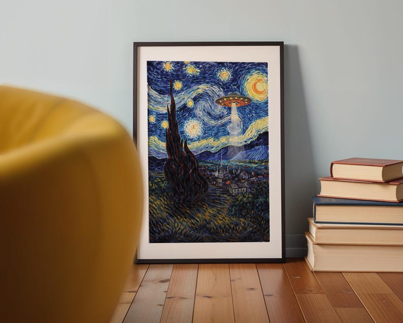 May include: Framed art print depicting a starry night scene with a UFO hovering above a village. The artwork features a dark, swirling sky with yellow stars and a crescent moon. The print is in a black frame and is propped against a light blue wall.