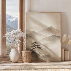 May include: A framed vertical wall art print featuring a monochromatic landscape of misty mountains and a lone pine tree in shades of beige and cream. The artwork is displayed in a light wood frame, positioned next to a white vase with dried flowers.